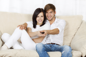 A young couple watches their wedding video snuggled on the couch